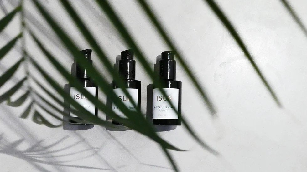 ISUN facial oils under palm leaf shadows